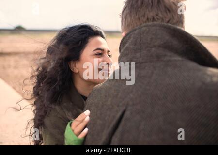 Glückliche Frau umarmt Freund am Strand Stockfoto