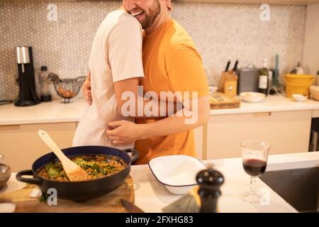 Glücklich Gay männliche paar Kochen und Umarmung in Küche Stockfoto