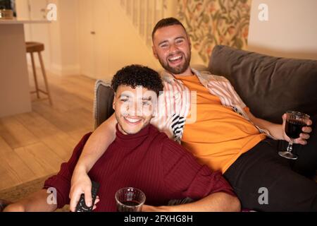 Portrait glücklich schwul männlich paar trinken Wein auf Sofa zu Hause Stockfoto