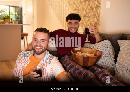 Glückliches schwules männliches Paar mit Wein und Popcorn beim Film Stockfoto