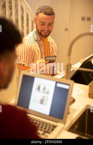 Junge schwule Paar arbeitet von zu Hause aus und mit Smartphone Stockfoto