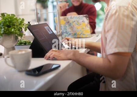 Junger Mann mit digitalem Tablet an der Küchentisch Stockfoto