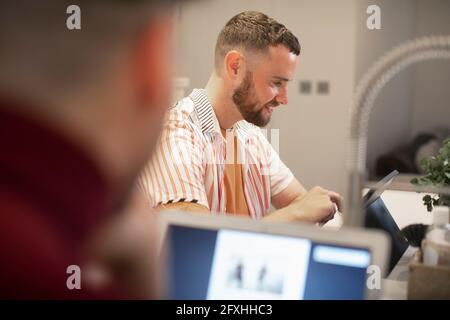 Glücklicher junger Mann, der von zu Hause aus am digitalen Tablet arbeitet Stockfoto