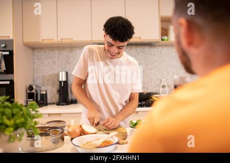 Junger Mann kocht Zwiebel schneiden in der Küche Stockfoto