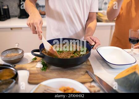 Junger Mann kocht Abendessen in der Küche Stockfoto