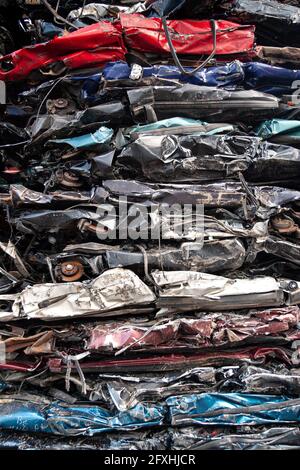 Stapel von gepressten Fahrzeugen in verschiedenen Farben aus einem Auto-Recycling-Zentrum. Stockfoto