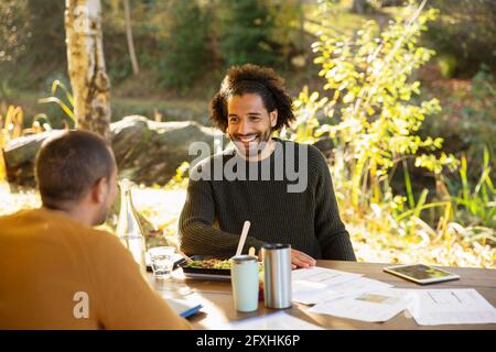 Geschäftsleute essen zu Mittag und diskutieren Papierkram am Parktisch Stockfoto