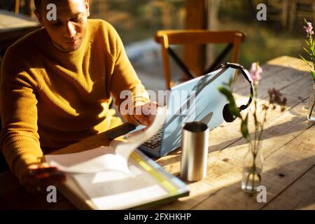 Geschäftsmann überprüft die Unterlagen am Laptop im Café Stockfoto