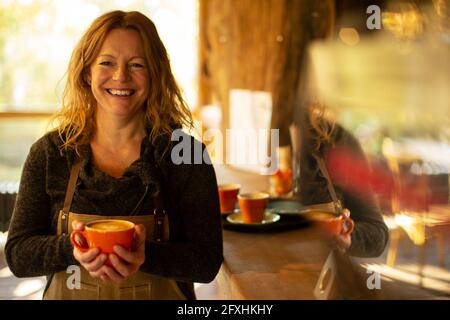 Portrait glückliche weibliche Café-Besitzer mit Cappuccino Stockfoto