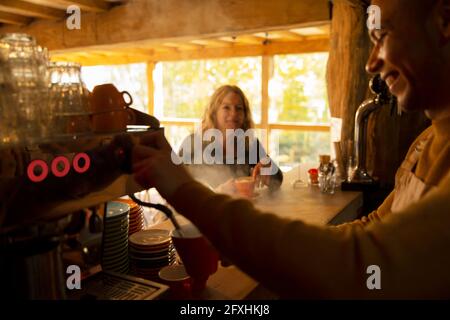 Barista bereitet den Kaffee für den Gast an der Espressomaschine im Café zu Stockfoto