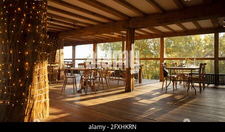 Holztische und -Stühle in einem sonnigen, leeren Restaurant Stockfoto