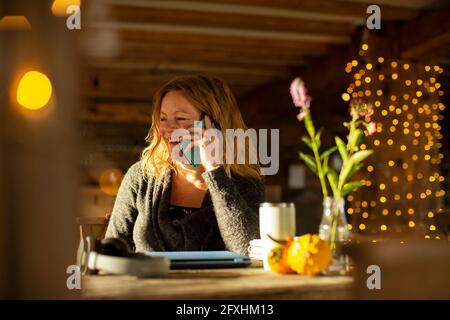Glückliche Geschäftsfrau, die im Café mit einem Smartphone spricht Stockfoto