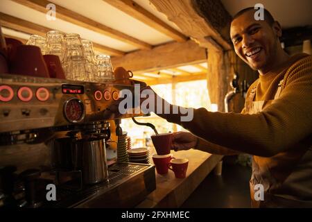 Portrait glücklicher Barista, der Kaffee an der Kaffeevollautomat zubereitet