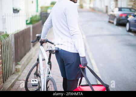 Männlicher Fahrradkurier, der Essen auf der städtischen Straße liefert Stockfoto