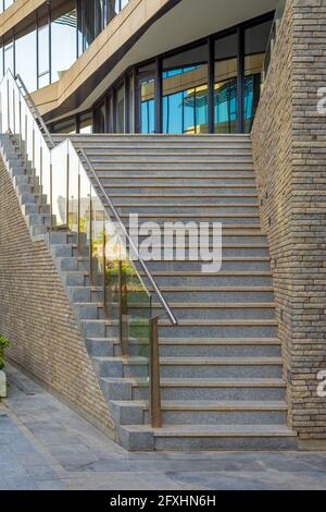 Steintreppe und Geländer führen zum Eingang der modernen Stadt Bürogebäude mit gläsernen Spiegelwänden Stockfoto