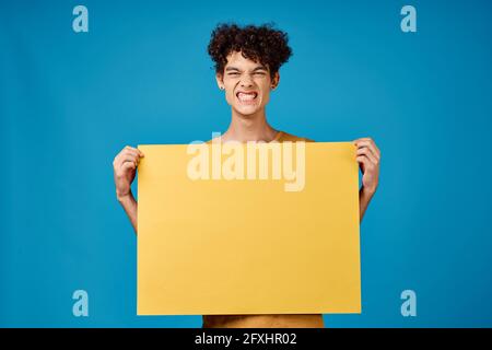 Lustige lockige Jungs mit einem gelb scharfen Werbung Copy Space Blauer Hintergrund Stockfoto