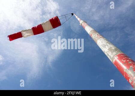Windsocke am Ende des abgestreiften Stabes flattert hinein Der Wind gegen den Himmel Stockfoto