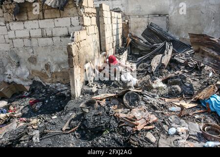 Manila. Mai 2021. Nach einem Brand in einem Slum in Manila auf den Philippinen am 27. Mai 2021 sucht ein Bewohner durch ein verkohltes Haus nach seinem Eigentum. Quelle: Rouelle Umali/Xinhua/Alamy Live News Stockfoto