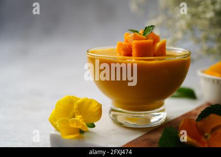 Hausgemachtes Mango-Mousse mit geschnittenen Mangos und Minze-Garnitur, selektiver Fokus Stockfoto