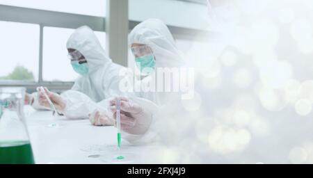 Zusammensetzung von Wissenschaftlern in psa-Anzügen mit funktionierenden Reagenzgläsern Im Labor- und Kopierbereich Stockfoto