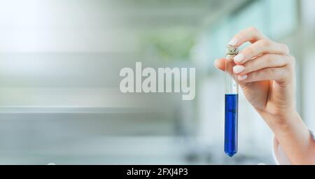 Zusammensetzung der Hand eines Labortechnikers, der das Reagenzglas mit blauer Flüssigkeit hält, mit verschwommenem Kopierraum Stockfoto