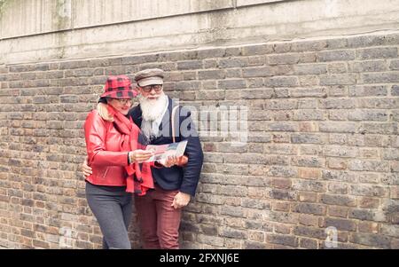 Seniorenpaar mit Stadtplan und Stadtführer auf der Straße. Rentner beim Lesen der Touristenkarte London. Liebe und fröhliche ältere Lifestyle-Konzept. Stockfoto