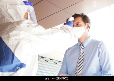 Experten zur Krankheitskontrolle verwenden ein Infrarot-Thermometer, um die Temperatur auf der Stirn zu überprüfen und Alkohol-Gel, um die Patienten hinzuzufügen Stockfoto