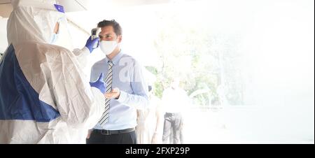 Experten zur Krankheitskontrolle verwenden ein Infrarot-Thermometer, um die Temperatur auf der Stirn zu überprüfen und Alkohol-Gel, um die Patienten hinzuzufügen Stockfoto