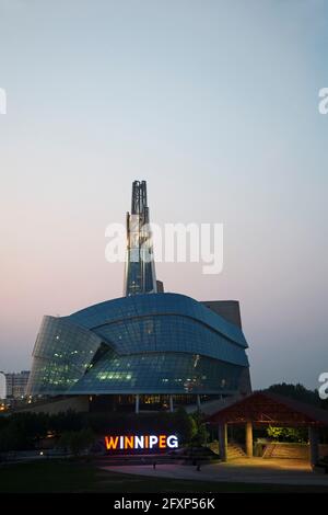 Beleuchtetes Windnipeg-Schild vor dem kanadischen Museum für Menschenrechte in Manitoba, Kanada. Das Museum wird gesehen, wie die Nacht über dem Ort fällt. Stockfoto