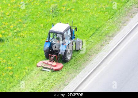 Traktor verwendet gezogene Rasenmäher, um Gras auf Stadtrasen zu mähen, Luftaufnahme Stockfoto
