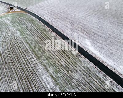 Luftaufnahme zum von Schnee und Straße bedeckten Winterfeld Stockfoto