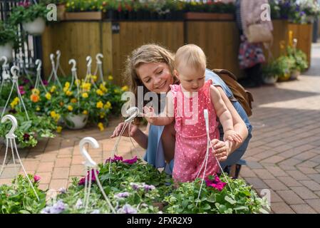 Frau mit Baby Tochter Garten Blumen auf Bauernmarkt an Sonniger Tag Stockfoto