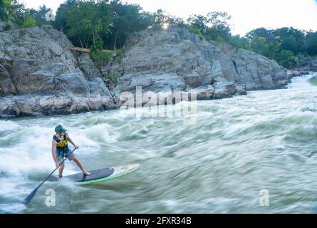 Ian Brown steht Up Paddle surft anspruchsvolles Wildwasser unter den Great Falls des Potomac River, der Grenze zwischen Maryland und Virginia, USA, Nordamerika Stockfoto