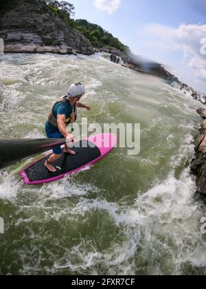 Der Fotograf Skip Brown steht auf dem Paddle unter den Great Falls des Potomac River, der Grenze zwischen Maryland und Virginia, USA, in anspruchsvollem Wildwasser Stockfoto