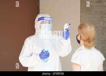 Experten zur Krankheitskontrolle verwenden ein Infrarot-Thermometer, um die Temperatur auf der Stirn zu überprüfen und Alkohol-Gel, um die Patienten hinzuzufügen Stockfoto