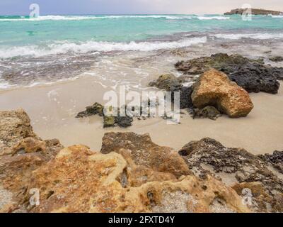 Leerer malerischer Nissi-Strand mit aufgewühlten türkisfarbenen Wasser, einer kleinen felsigen Insel und einem dunklen, wolkigen Himmel in Ayia Napa, Zypern. Herrlicher Urlaub am Meer. Stockfoto