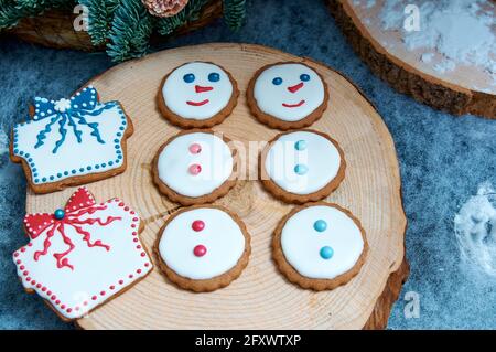 Fröhliche Lebkuchenschneemänner auf einem Holzblock. Weihnachtsgeschenk. Stockfoto
