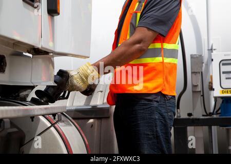 LKW-Fahrer betankt Transport-LKW trägt Sicherheitsweste Stockfoto