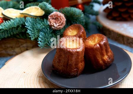 Kleine Cupcakes auf einer schwarzen Untertasse. Ein Teil des Weihnachtstisches, im Hintergrund Weihnachtsdekorationen aus Tanne. Holztablett Stockfoto