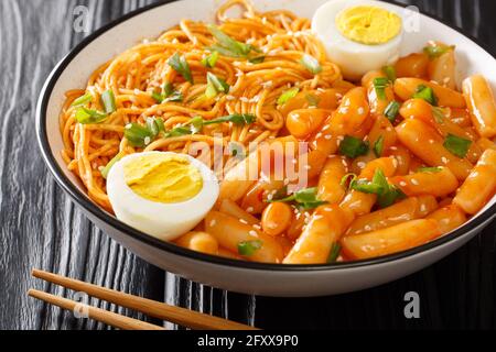 Spicy Rabokki ist eine Variation von Tteokbokki mit Ramen Nudeln mit gekochten Eiern in der Schüssel auf dem Tisch serviert. Horizontal Stockfoto