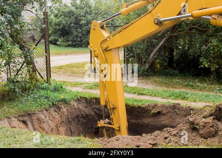 Der Hydraulikkolben des Baggers gräbt mit einem Industriekübel auf der Baustelle tief in die Grube. Stockfoto