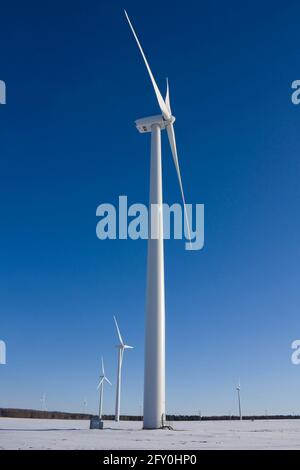 Windturbine im verschneiten Feld gegen blauen Himmel Stockfoto