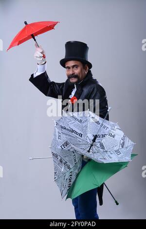 Zauberer macht Tricks mit Regenschirmen auf weißem Hintergrund Stockfoto