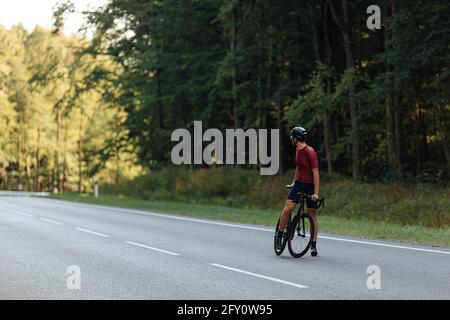 Radprofi steht auf asphaltierter Straße mit Fahrrad Stockfoto