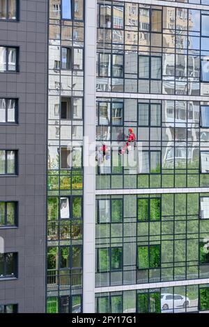 Jekaterinburg, Russland, 10. Mai 2020: Zwei Industriekletterer des Reinigungsdienstes waschen die Glasfassade eines modernen Hochhauses. Stockfoto