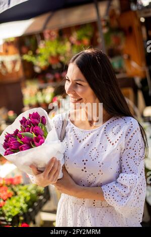 Hübsche junge Frau, die Blumen auf dem Blumenmarkt kauft Stockfoto