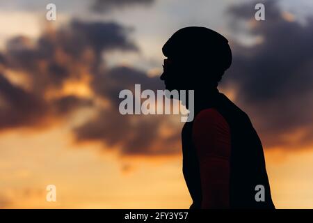 Silhouette eines Mannes, der den Sonnenuntergang während des Straßenrennens genießt Stockfoto