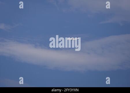 Propellerflugzeug von der Sonne gegen einen blauen Himmel beleuchtet Mit weißen Wolken und Baum - in Bewegung Stockfoto