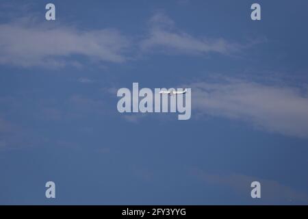 Propellerflugzeug von der Sonne gegen einen blauen Himmel beleuchtet Mit weißen Wolken und Baum - in Bewegung Stockfoto