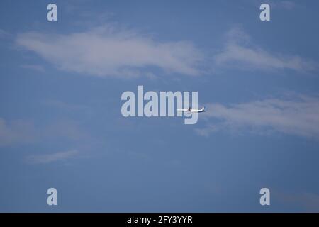 Propellerflugzeug von der Sonne gegen einen blauen Himmel beleuchtet Mit weißen Wolken und Baum - in Bewegung Stockfoto